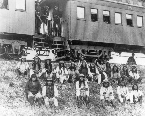 Black and white historical photograph of Apache leader Geronimo and his warriors as prisoners of war before arriving at Fort Pickens in Pensacola, Florida.
