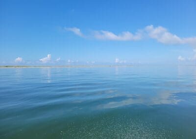 Perfectly smooth, glassy water and clear blue skies over the Santa Rosa Sound, offering a relaxing and peaceful view during a private Pensacola boat cruise.