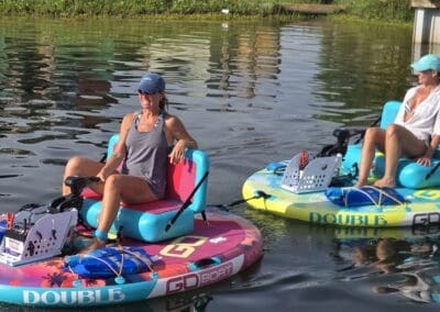 Close up of two women relaxing on a pink and a blue motorized float boat in Pensacola Beach, Florida.