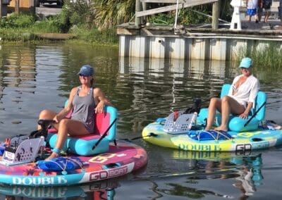 Two women enjoying motorized double float boats on the water near Sabine Marina in Pensacola Beach.