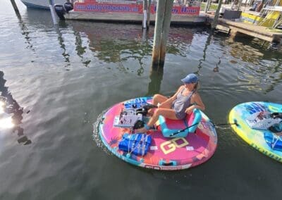 A smiling woman steering a pink motorized double float boat next to a charter boat at Sabine Marina.