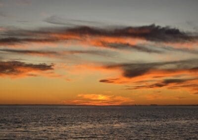 The sun setting just above the horizon, viewed from a private captained sunset tour departing Sabine Marina.